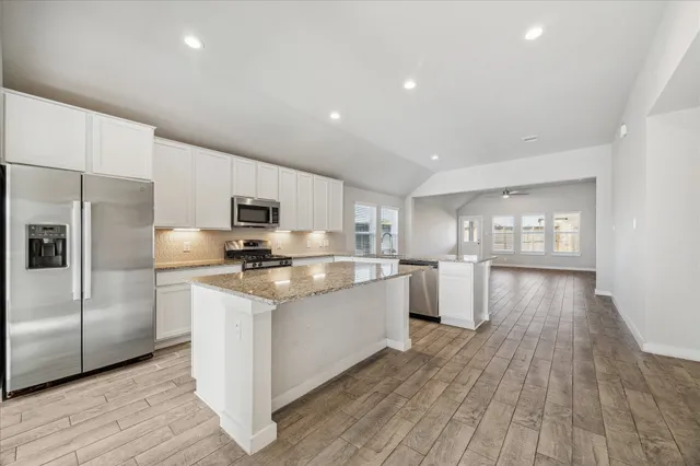 a kitchen with stainless steel appliances granite countertop a white cabinets and wooden floor