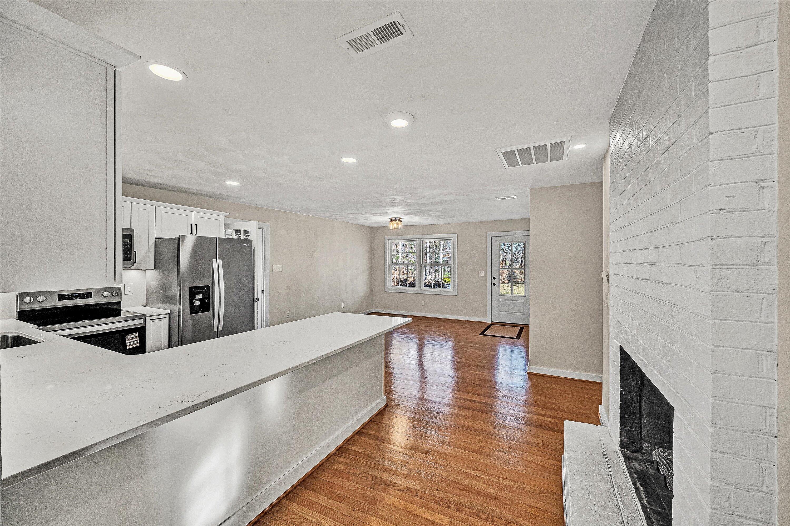 4883 Edwardsville Road Hardy, VA 24101 - Photo 13 of 32 a large white kitchen with stainless steel appliances refrigerator a oven and a fireplace with wooden floor