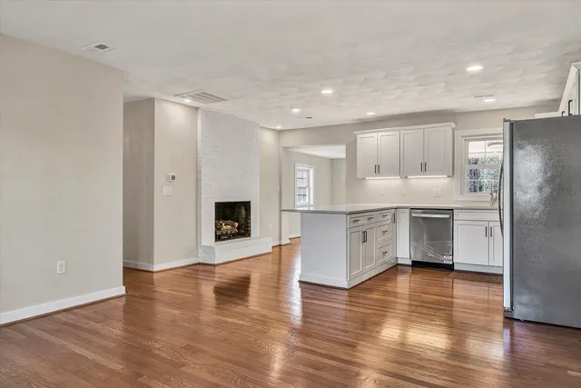 a large white kitchen with stainless steel appliances granite countertop a large counter top and a stove with wooden floor
