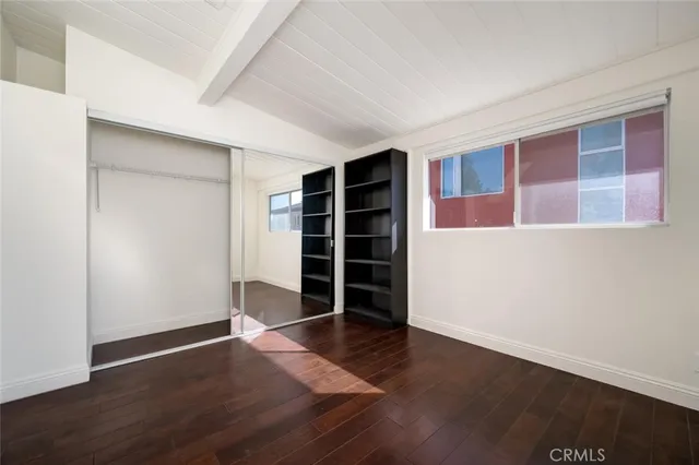 a view of an empty room with wooden floor and closet