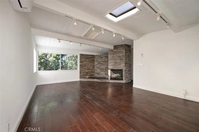 an empty room with wooden floor fireplace and windows