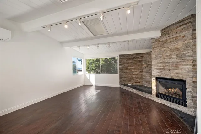 an empty room with wooden floor fireplace and windows