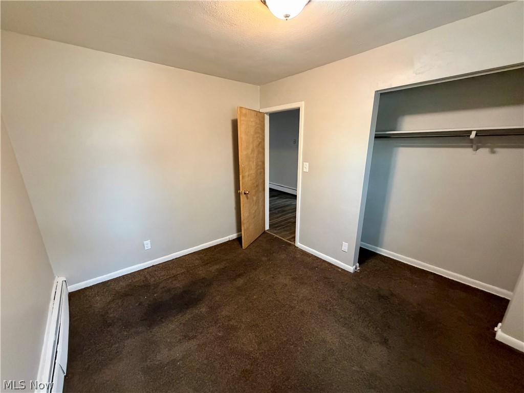 4652 Warner Road, Unit 3 Cleveland, OH 44125 - Photo 13 of 13 Unfurnished bedroom featuring a baseboard heating unit, dark colored carpet, and a closet