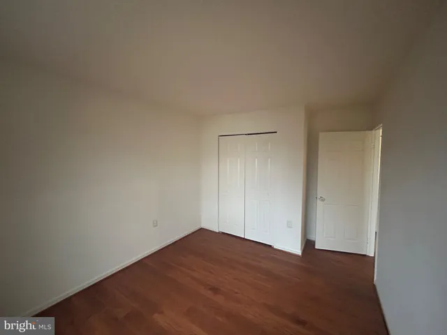a view of an empty room with wooden floor and closet