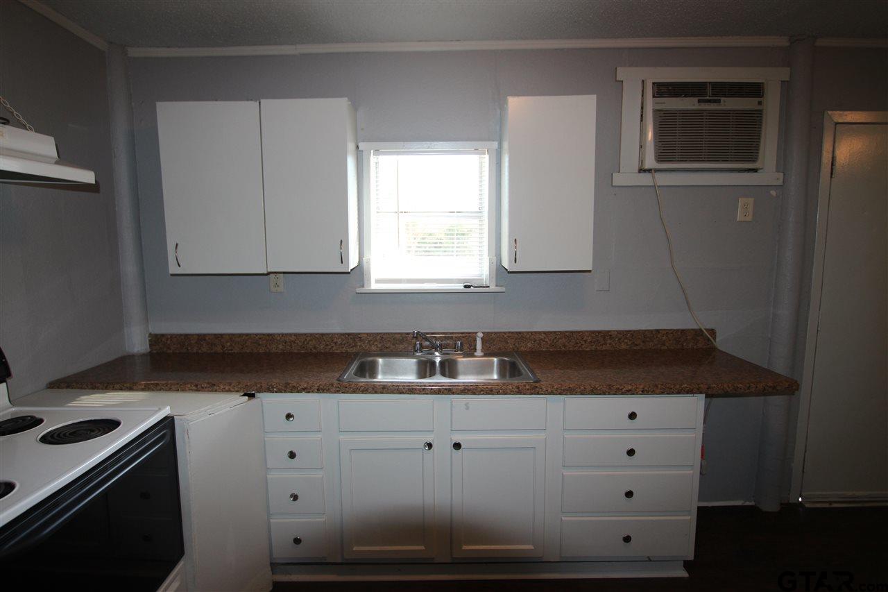 4229 Old Chandler Road, Unit B Tyler, TX 75702 - Photo 11 of 17 a kitchen with granite countertop white cabinets and white appliances