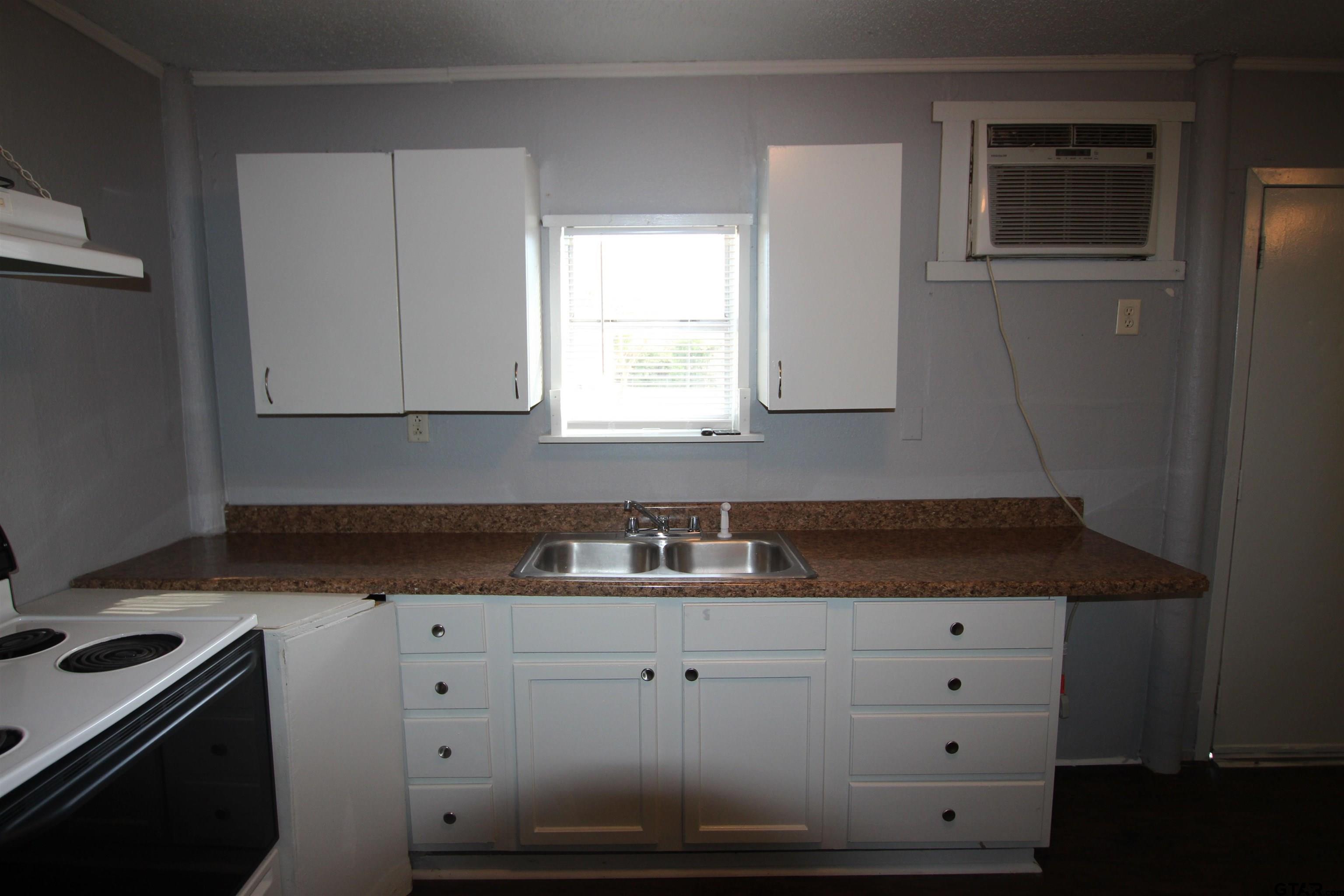 4229 Old Chandler Road, Unit B Tyler, TX 75702 - Photo 13 of 17 a kitchen with granite countertop white cabinets and white appliances