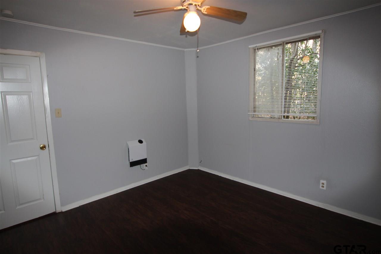 4229 Old Chandler Road, Unit B Tyler, TX 75702 - Photo 6 of 17 an empty room with wooden floor chandelier fan and windows