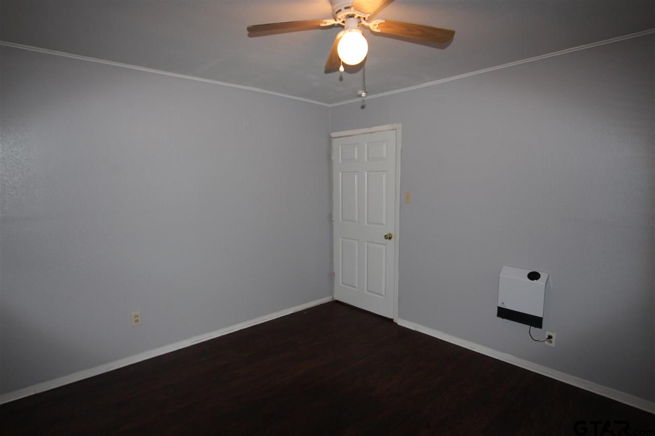 4229 Old Chandler Road, Unit B Tyler, TX 75702 - Photo 7 of 17 an empty room with a chandelier fan and wooden floor