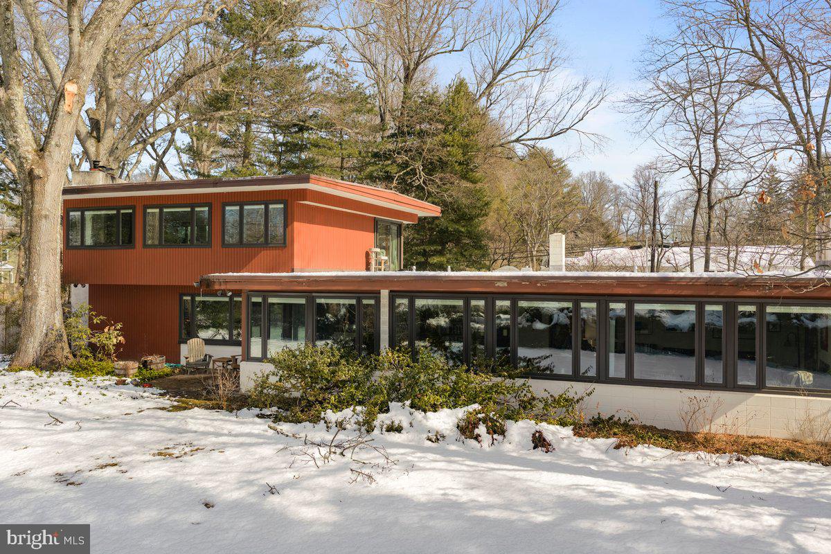 a front view of a house with a yard covered with snow and trees