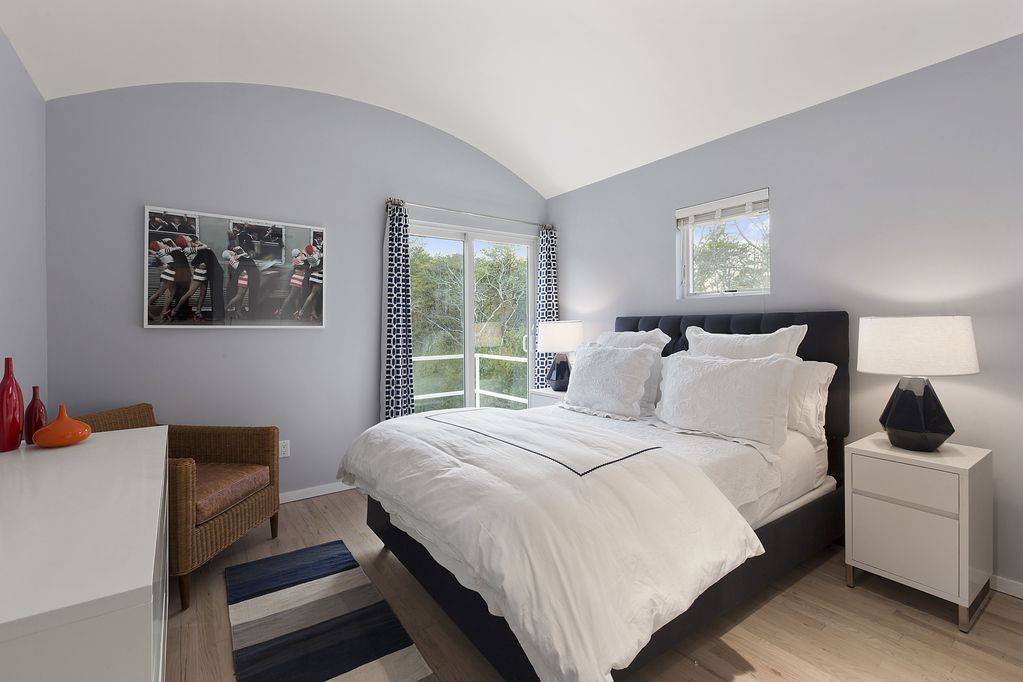 165 2 Holes Water Road East Hampton, NY 11937 - Photo 10 of 19 a bedroom with a bed a lamp and a window