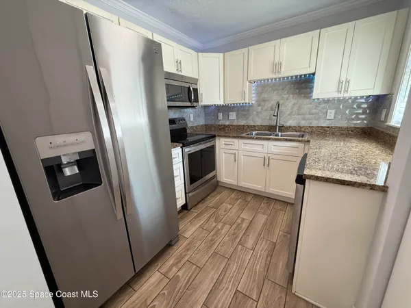 a kitchen with stainless steel appliances granite countertop a refrigerator a sink a stove a microwave a sink and dishwasher