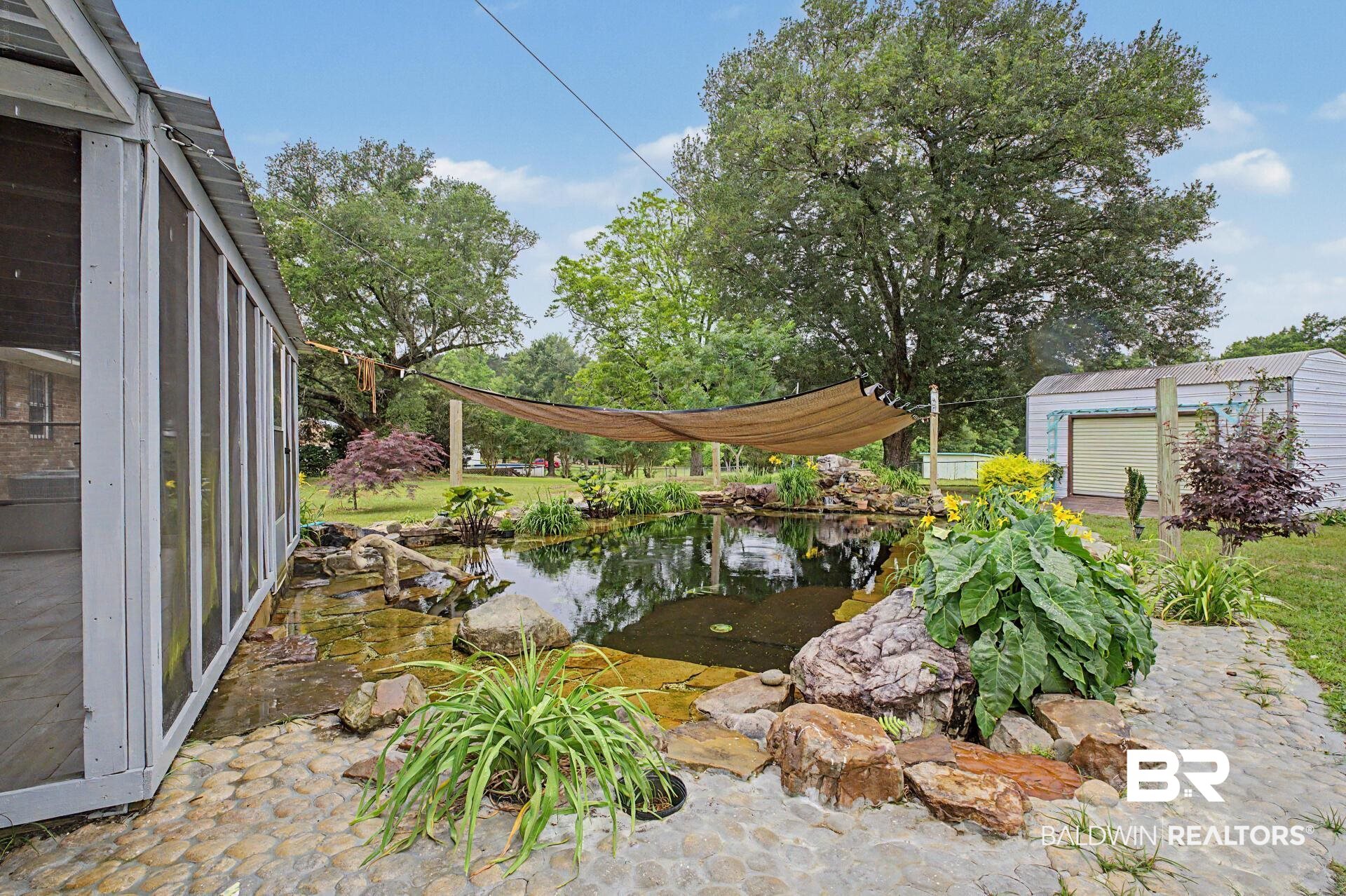 3791 Robinsonville Road Atmore, AL 36502 - Photo 14 of 47 Screened patio opening to a stone-lined pond with surrounding landscaping