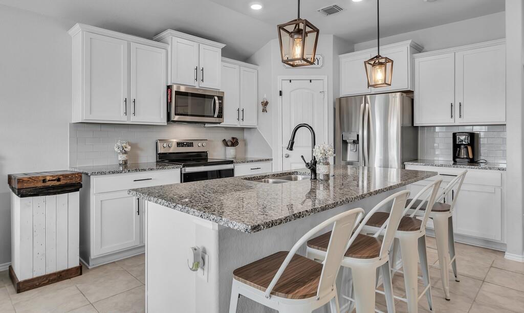 11108 Beckon Falls Waco, TX 76708 - Photo 7 of 32 a kitchen with stainless steel appliances granite countertop a sink a microwave a refrigerator and white cabinets
