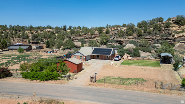 1504 Rome Way Apple Valley, UT 84737 - Photo 22 of 22 Single-story residence featuring a covered front porch, integrated solar panels, and a red detached outbuilding