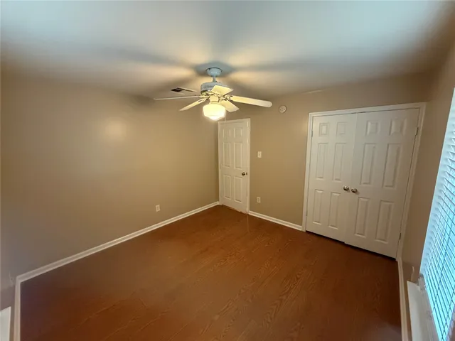 an empty room with a chandelier fan and windows