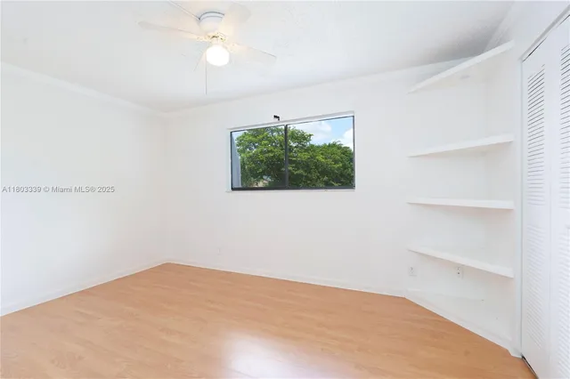 a view of empty room with wooden floor and fan