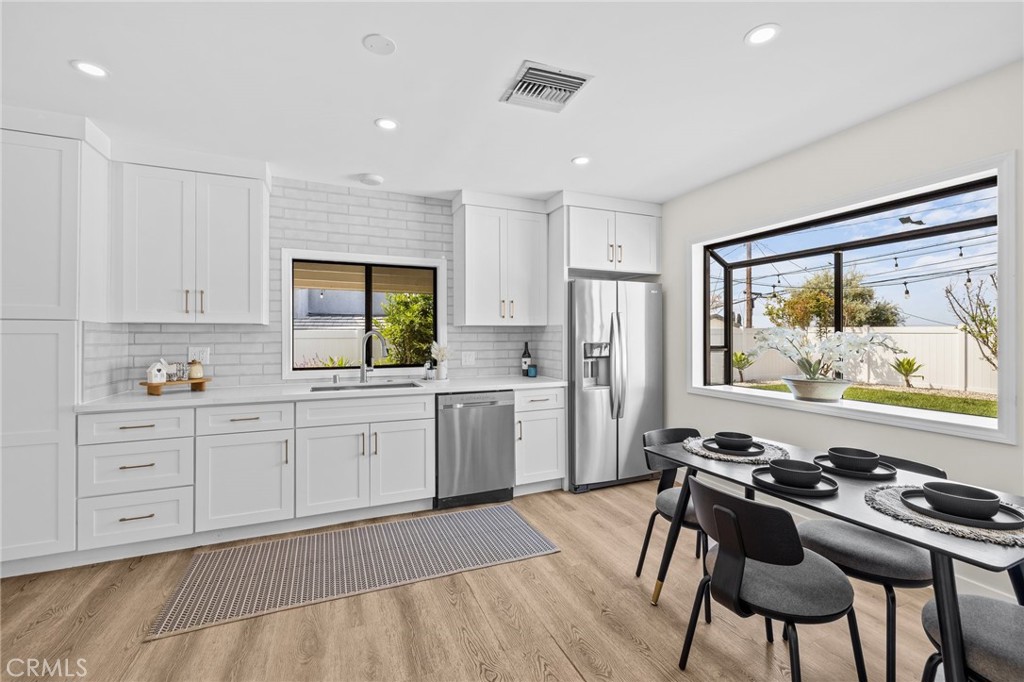 3045 Scott Road Burbank, CA 91504 - Photo 11 of 39 a kitchen with stainless steel appliances a stove a sink dishwasher and white cabinets with wooden floor