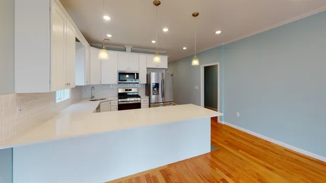 a large kitchen with stainless steel appliances a large counter top and wooden floors