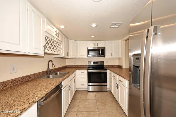 a kitchen with granite countertop white cabinets and stainless steel appliances