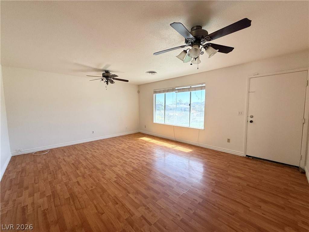 616 Greenway Road Henderson, NV 89002 - Photo 5 of 32 Natural light illuminates the open living space, featuring polished wood flooring and twin ceiling fans.