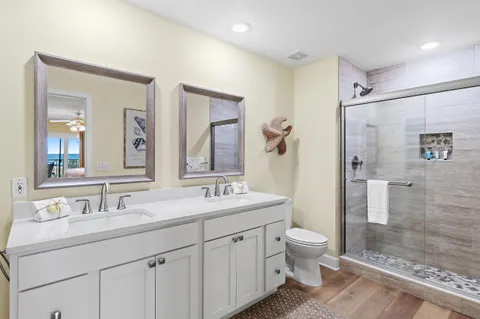 a bathroom with a double vanity sink toilet mirror and shower
