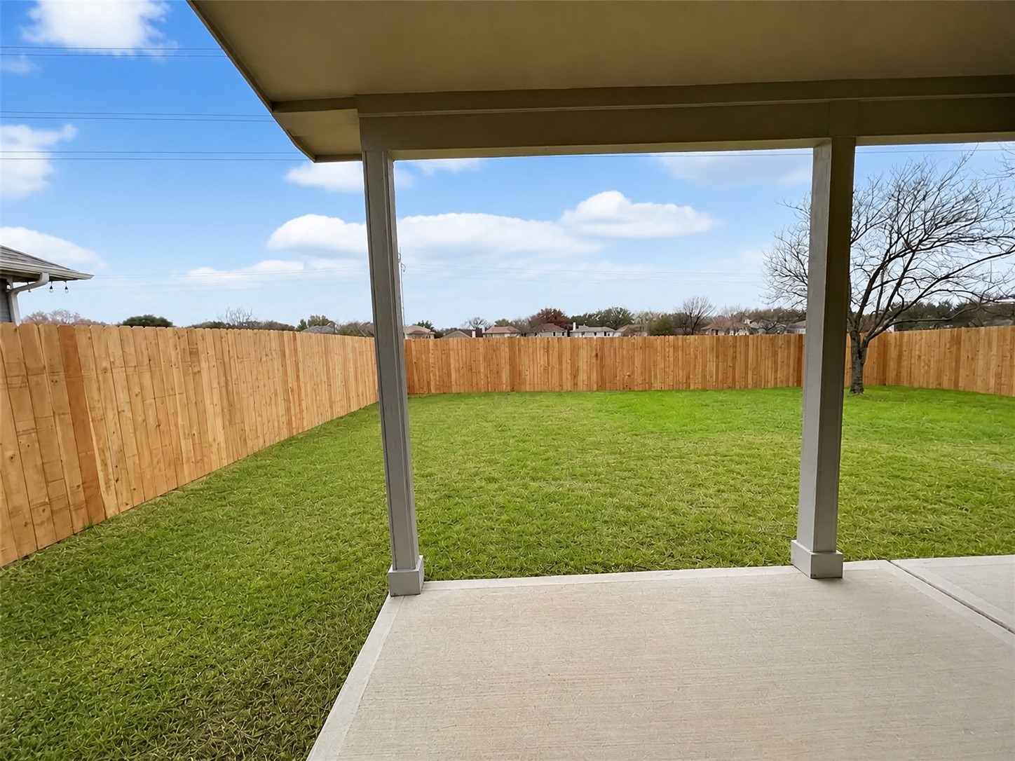 14828 Single Trace Austin, TX 78728 - Photo 24 of 30 Covered patio with a concrete slab, expansive green lawn, and a perimeter wood fence
