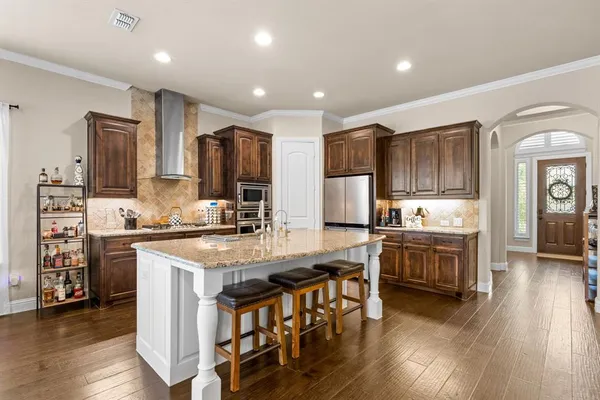 a kitchen with stainless steel appliances granite countertop wooden cabinets a stove a sink and a center island