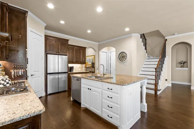 a kitchen with stainless steel appliances granite countertop a refrigerator a stove a sink dishwasher and a refrigerator with wooden floor