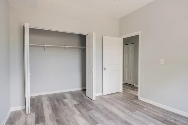 a view of an empty room with wooden floor and closet