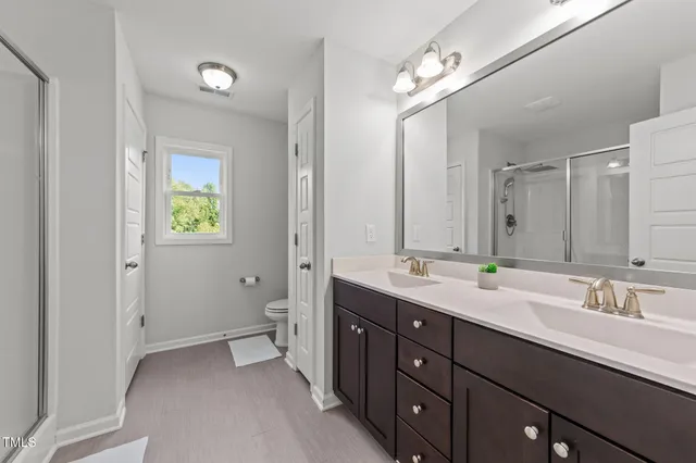 a spacious bathroom with a double vanity sink toilet and a mirror
