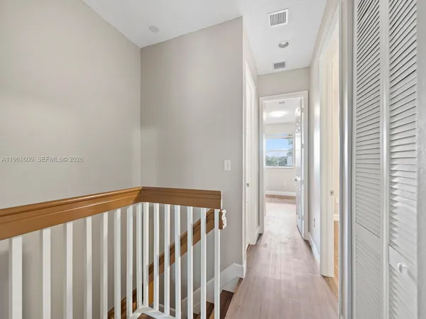a view of a hallway with wooden floor and a bathroom