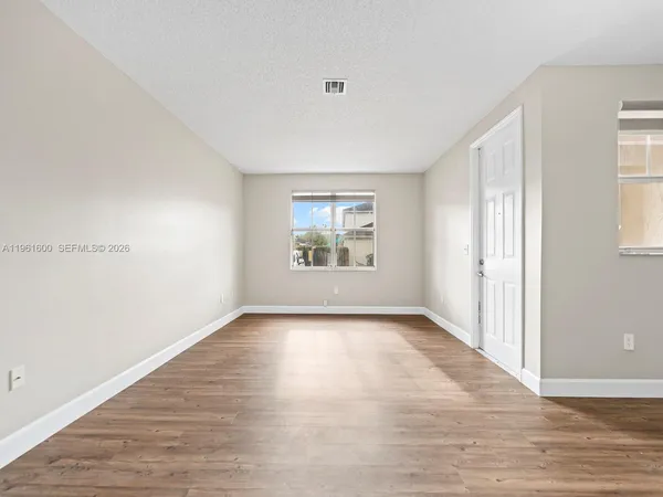 an empty room with wooden floor cabinet and windows