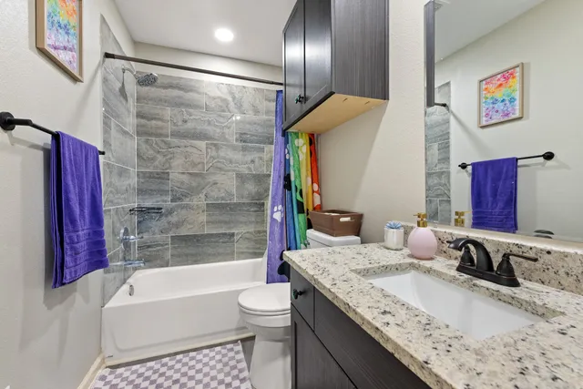 a bathroom with a granite countertop sink a mirror a bathtub and shower