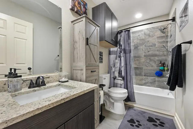 a bathroom with a granite countertop sink toilet and shower