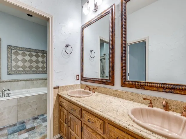 a bathroom with a granite countertop double vanity sink a mirror and a bathtub