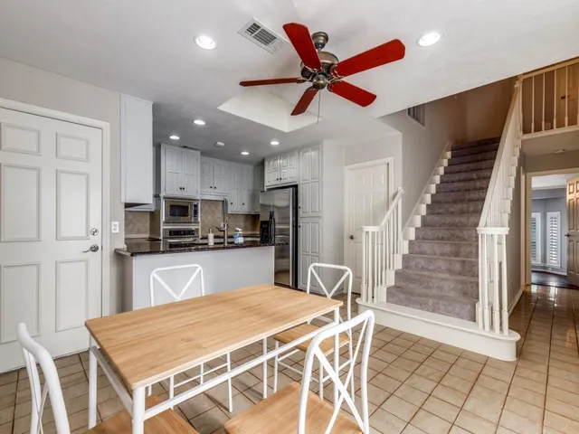 a kitchen with stainless steel appliances kitchen island granite countertop a refrigerator a stove top oven and a sink with wooden floor