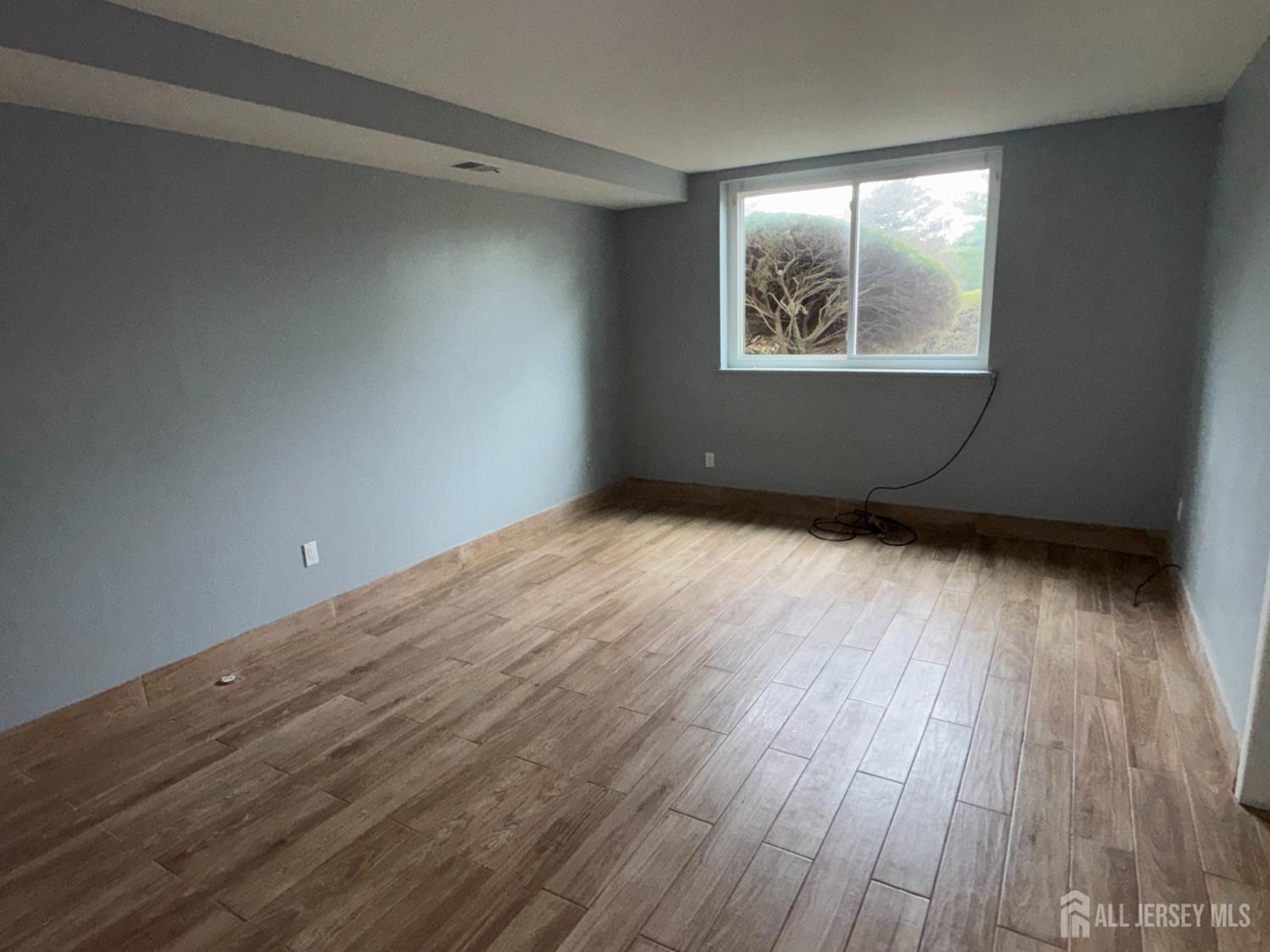 76 College Drive Edison, NJ 08817 - Photo 12 of 16 an empty room with wooden floor and windows