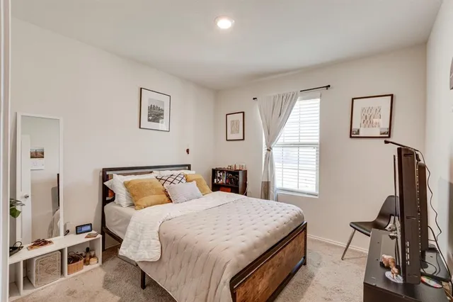 a bedroom with a bed and a flat tv screen on a dresser