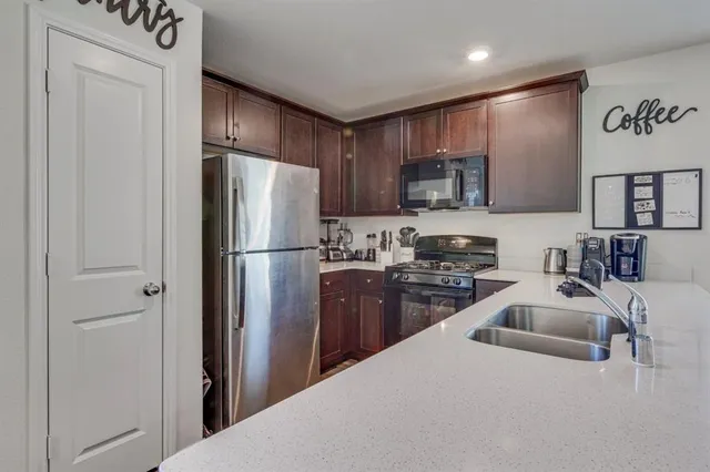 a kitchen with granite countertop stainless steel appliances a refrigerator a stove a sink and a refrigerator