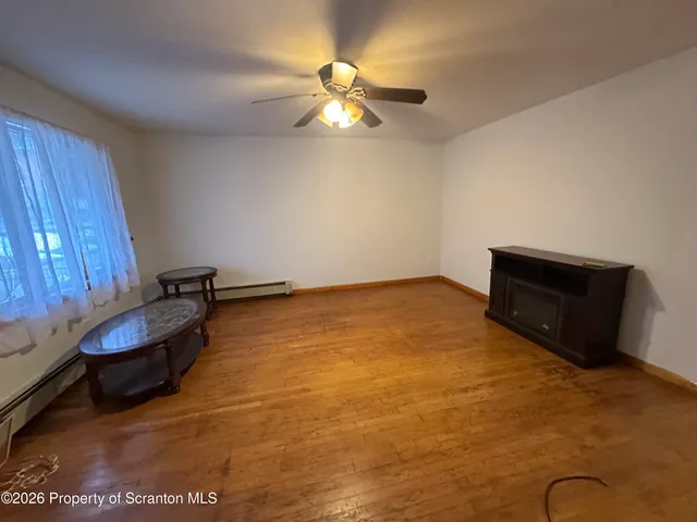 a room with wooden floor and ceiling fan