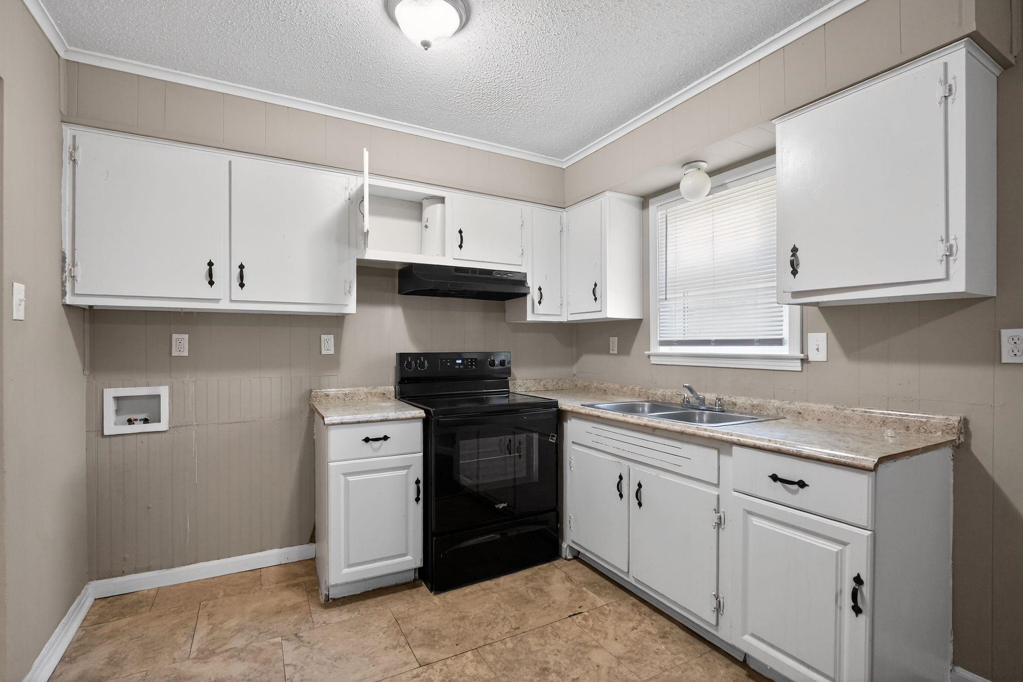 4587 Appleville Street Memphis, TN 38109 - Photo 19 of 34 Kitchen featuring black range with electric stovetop, wooden walls, light countertops, white cabinetry, and a textured ceiling