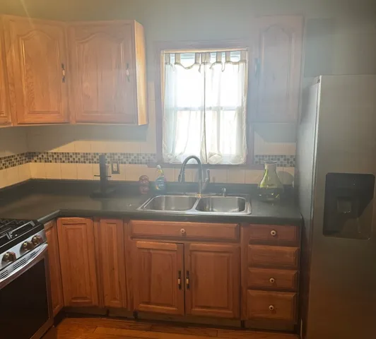 a kitchen with granite countertop a sink cabinets stainless steel appliances and a window