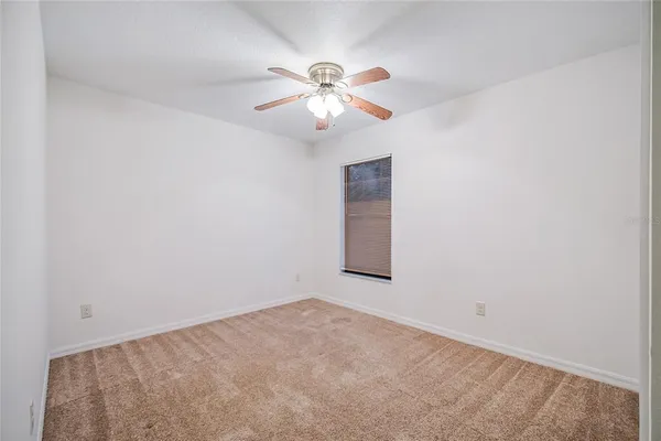 an empty room with a window and a chandelier fan