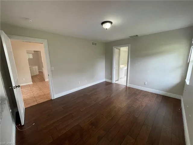 an empty room with wooden floor and mirror
