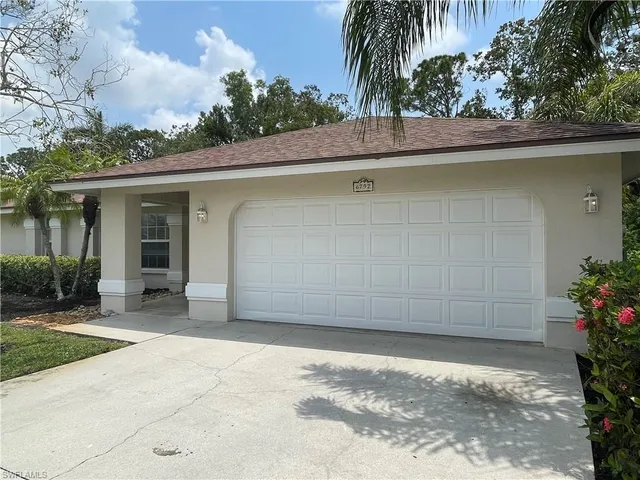 a backyard of a house with potted plants and palm tree