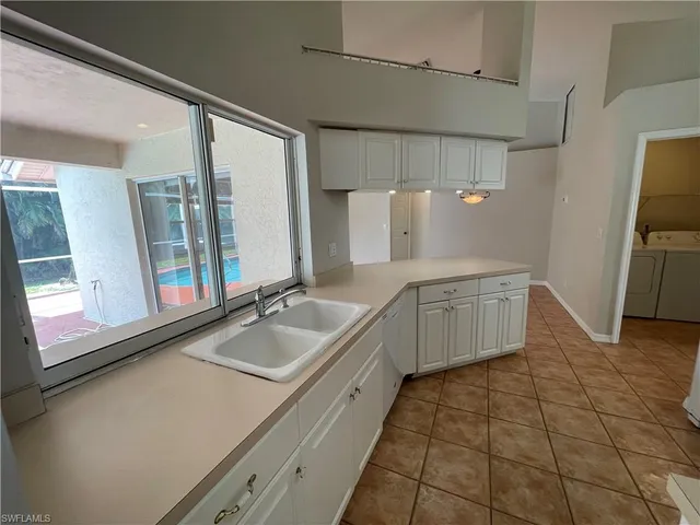 a large white kitchen with a sink a refrigerator and window