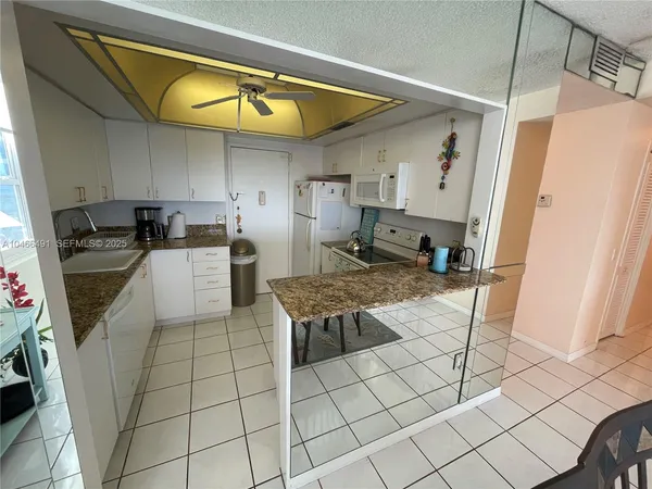 a living room with stainless steel appliances furniture a rug and a refrigerator