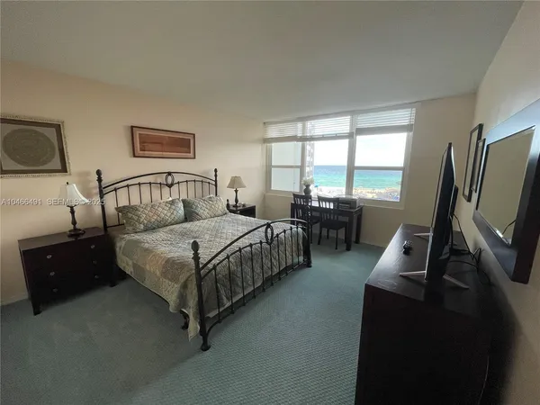 a bedroom with a bed window and flat screen tv