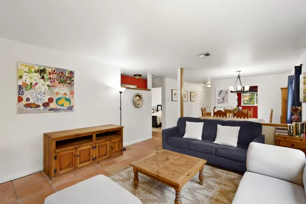 a living room with furniture and a dining table with bookshelf