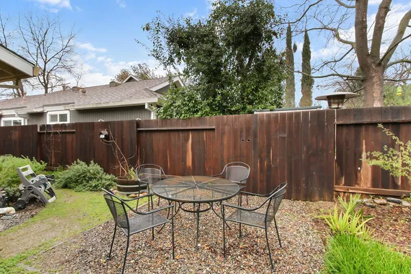 a view of a chairs and table in the back yard of a house
